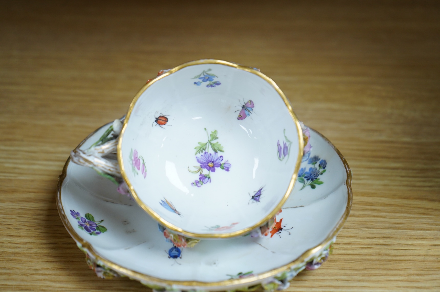 A 19th century Meissen floral encrusted cup and saucer, 14cm diameter